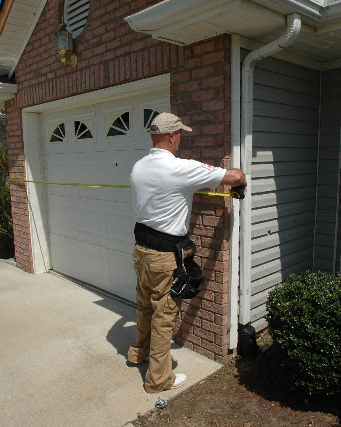 Insurance adjuster examining the front of a storm-damaged home