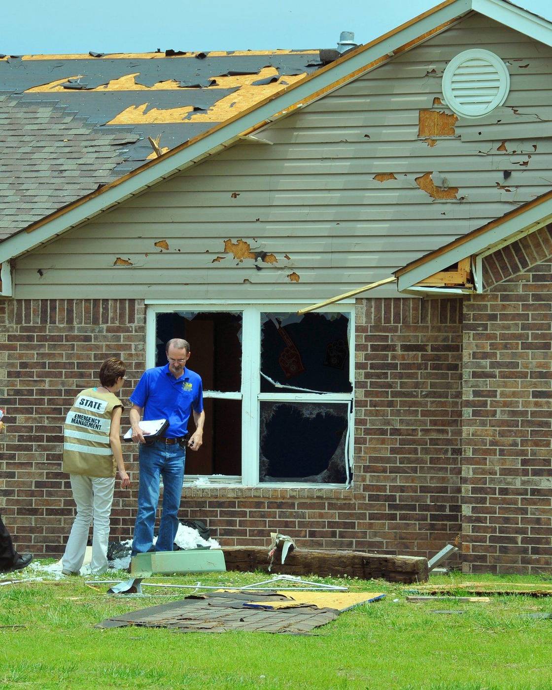 Assessment team discussing findings outside a storm-damaged brick house