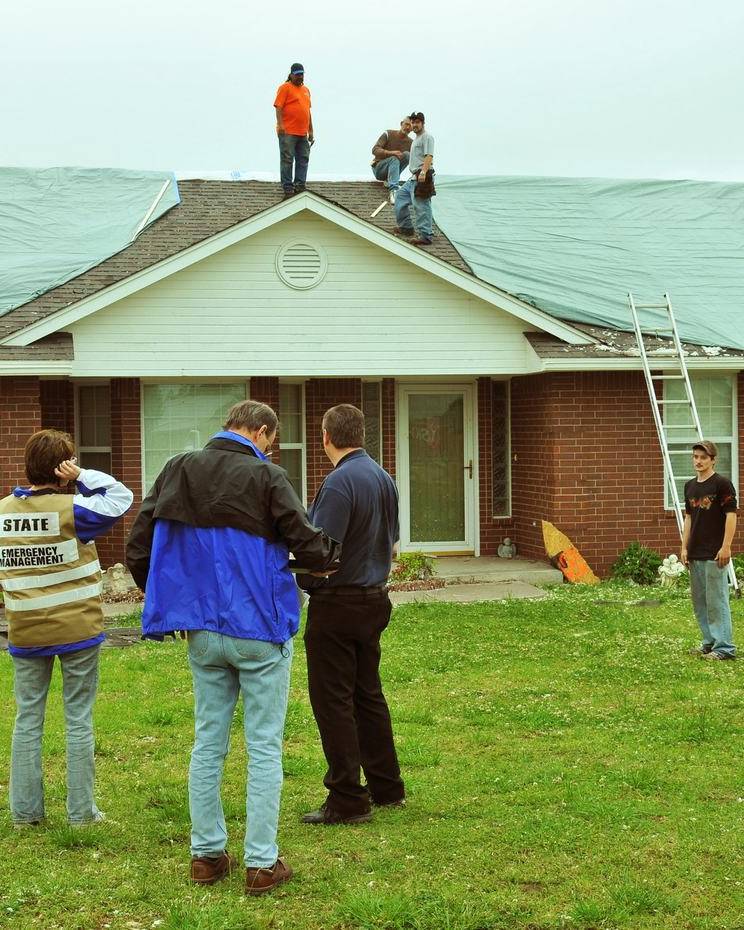Assessment team outside a house as roofers work above them