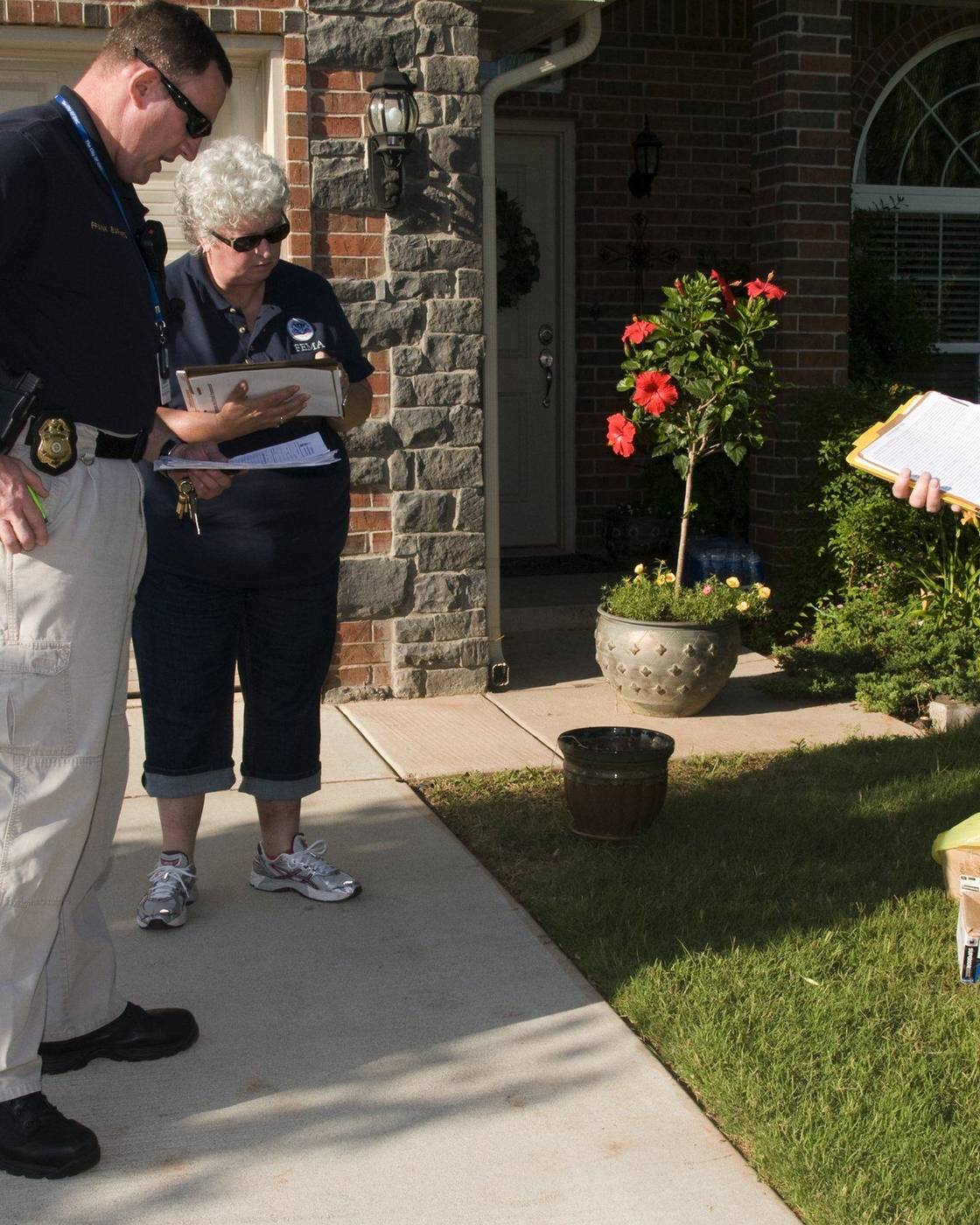 Damage assessors talking with a homeowner outside his house