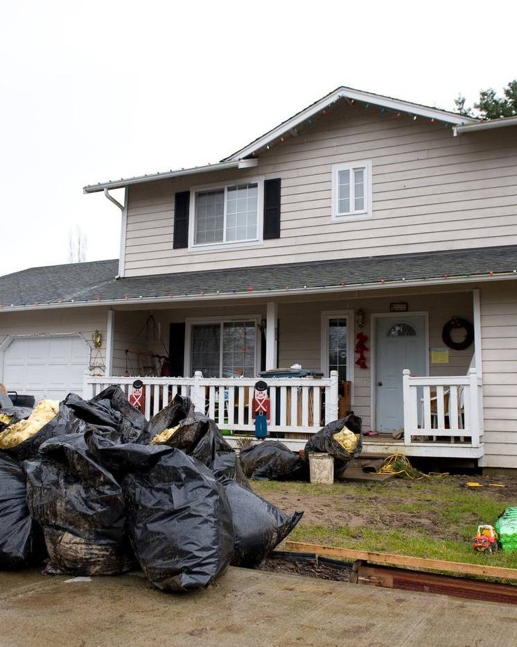 Bags of gutted flood debris piled outside a two-storey house