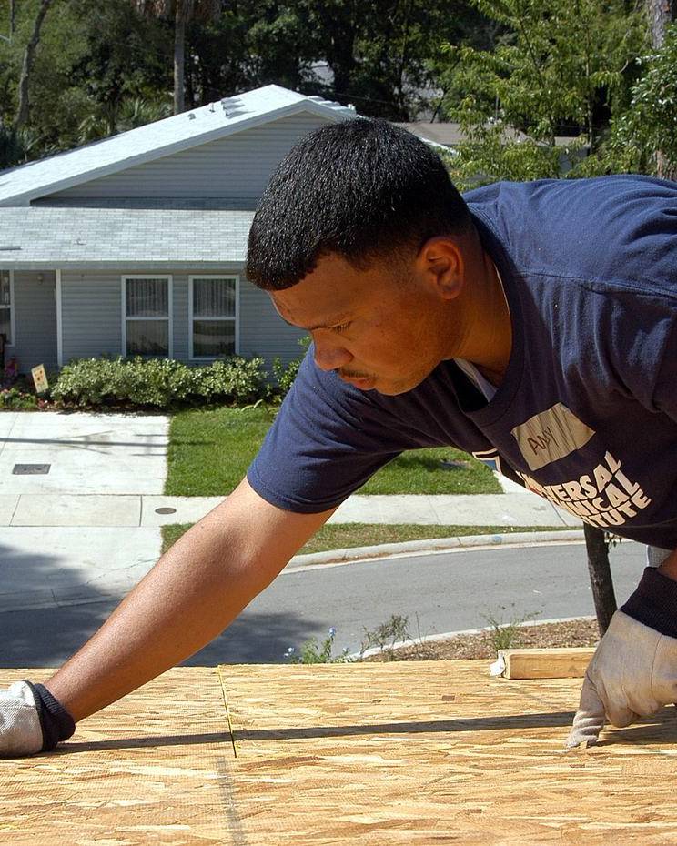 Builder fixing plywood sheathing on the roof of a new home in Atlantic Beach, Florida