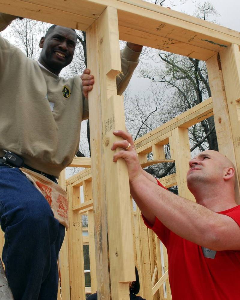 Two builders fitting timber wall framing inside a new house