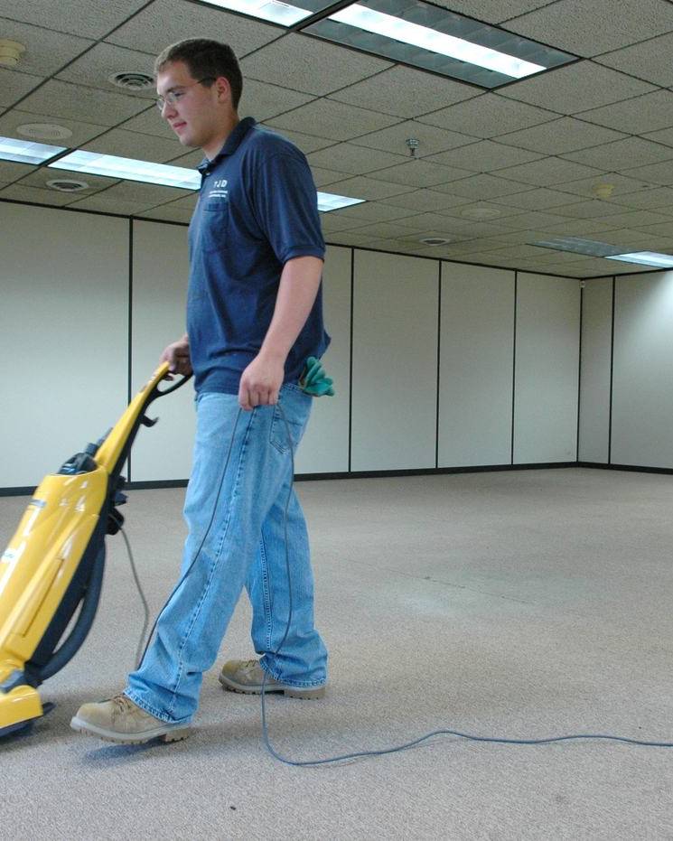 Worker vacuuming the carpet of an empty office