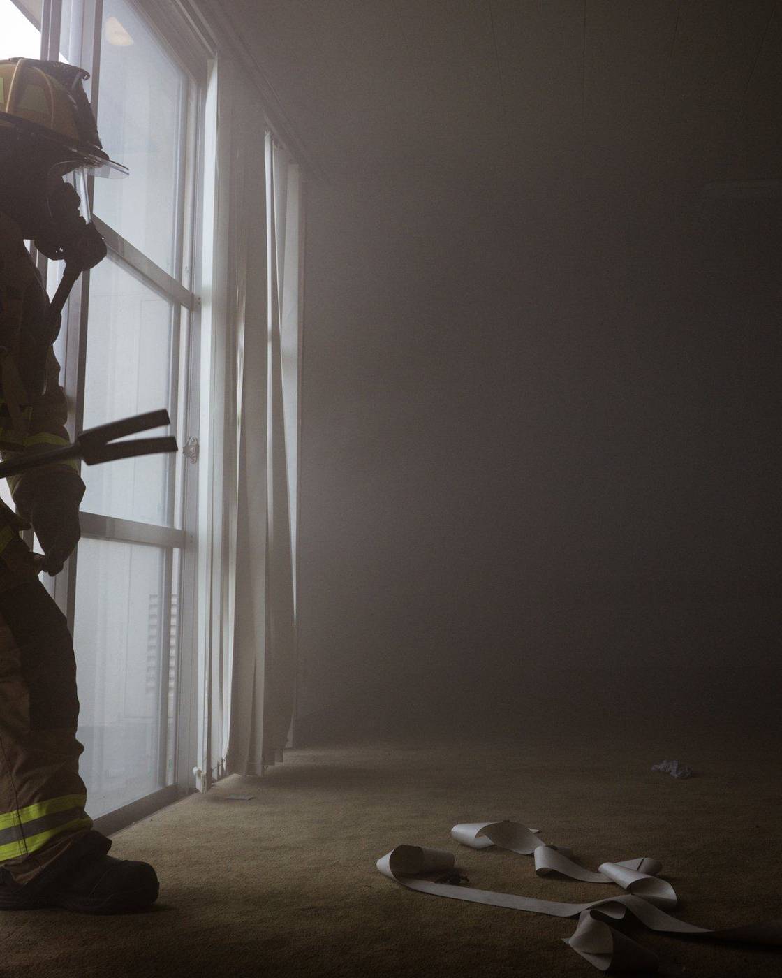 Firefighter in breathing gear moving through a smoke-filled room