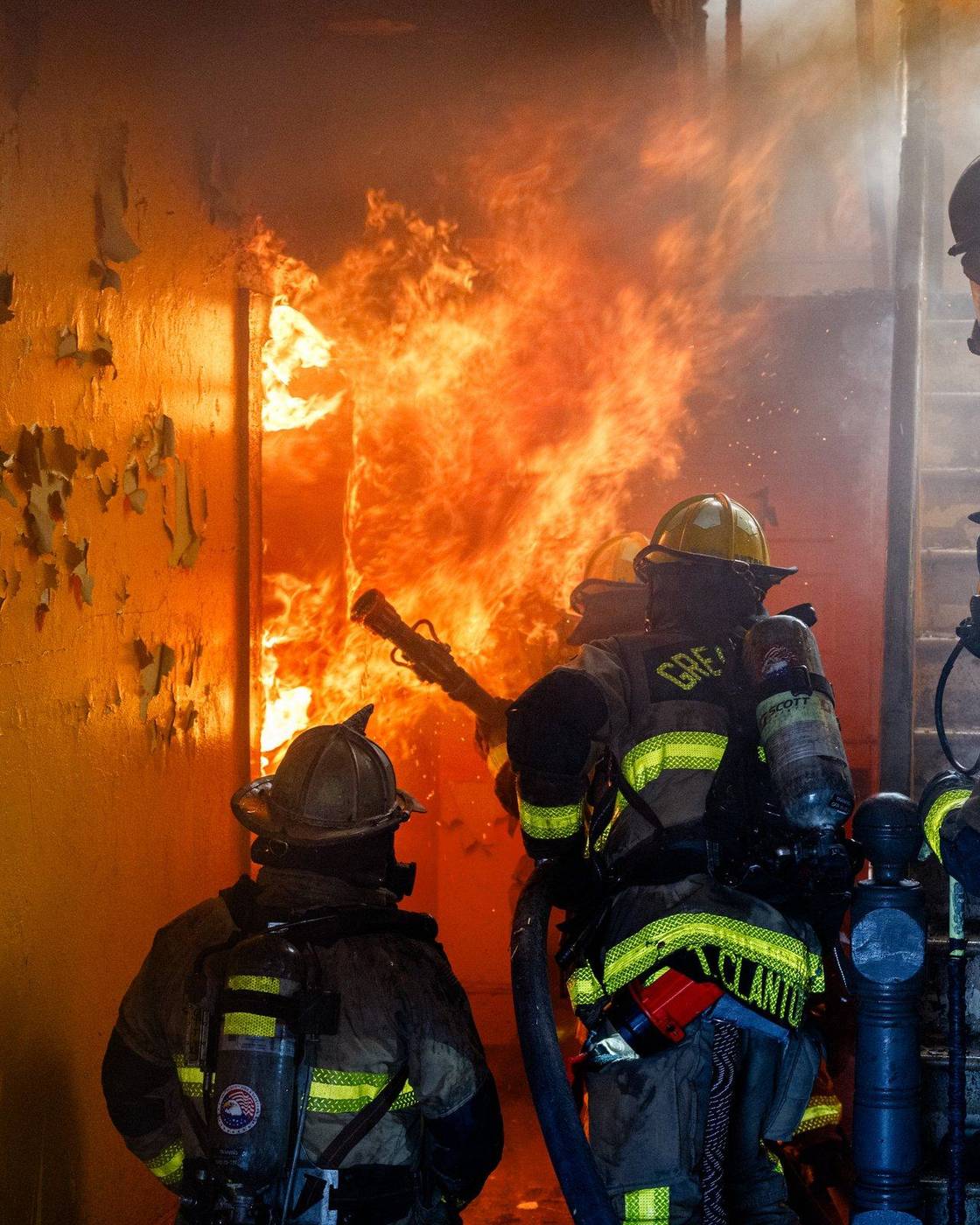 Firefighters in breathing gear inside a burning room