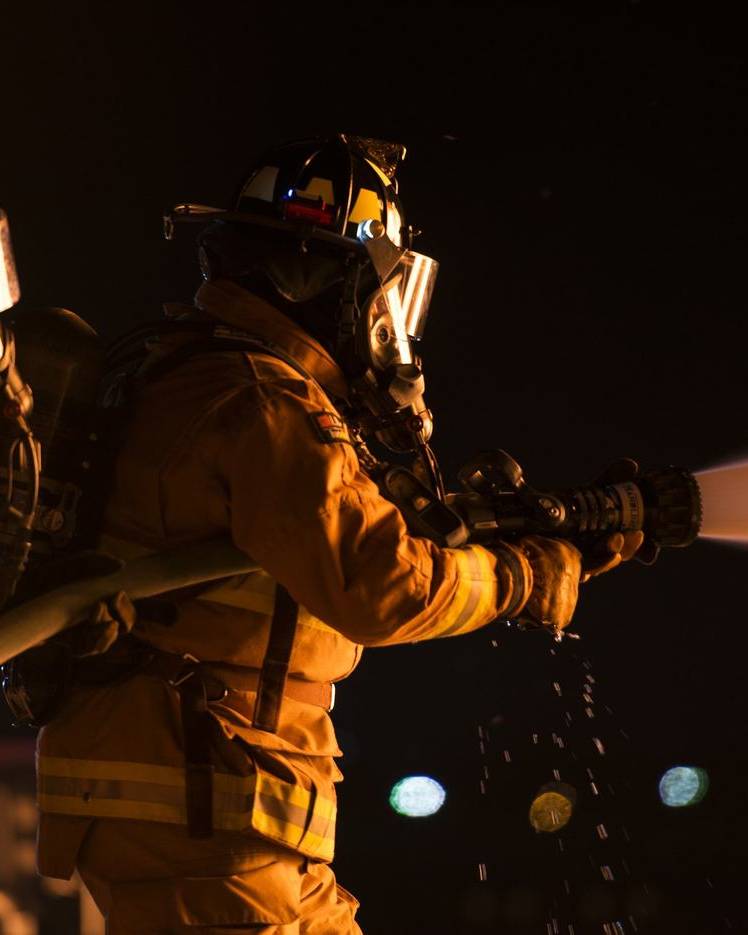 Two firefighters spraying water at night