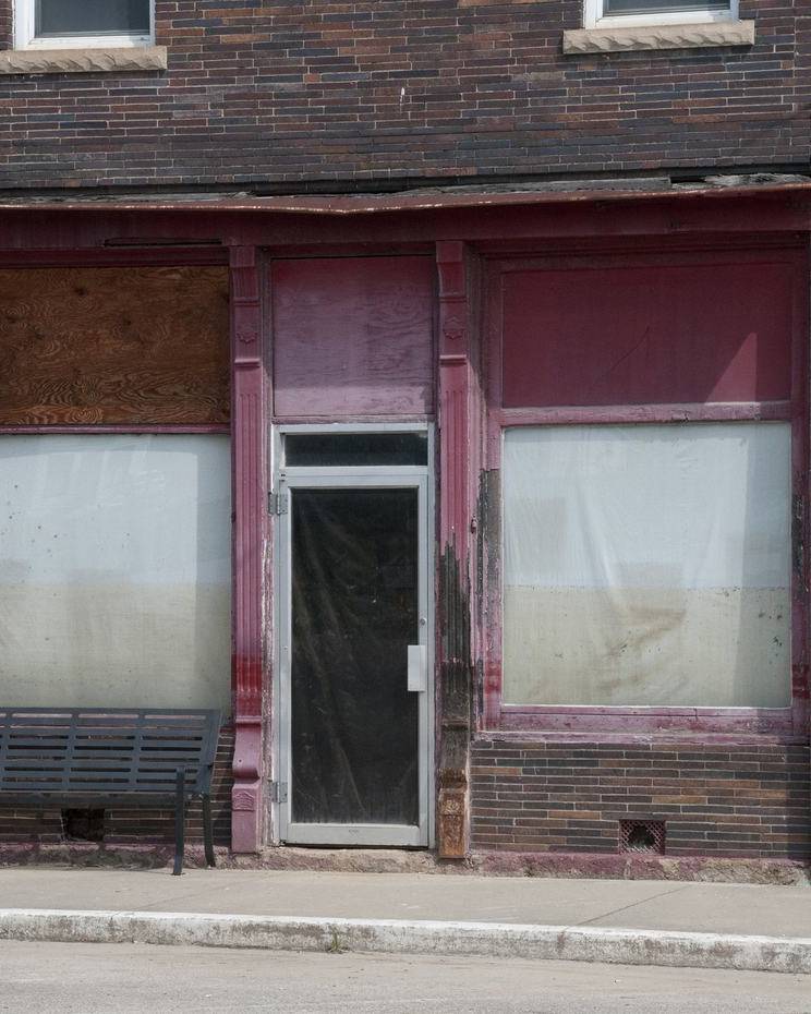 Flood-damaged brick storefront with boarded windows