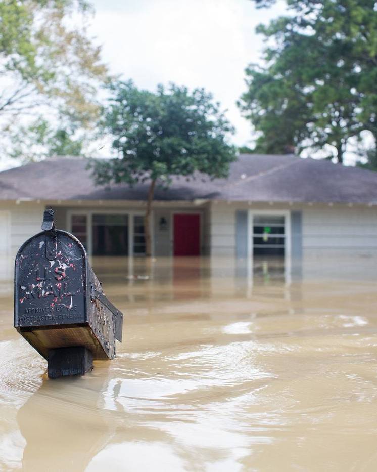 Flood water up to the windows of a house, with only the mailbox showing