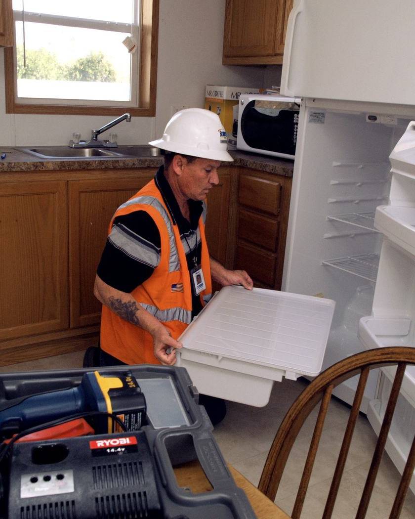 Inspector in a hard hat checking a kitchen and its appliances