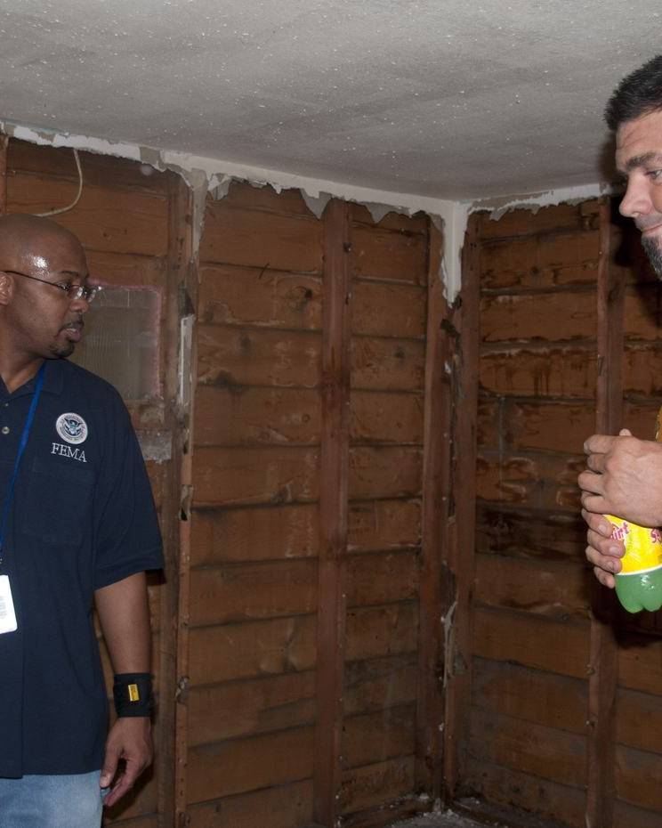Inspector with a clipboard in a gutted room with the homeowner