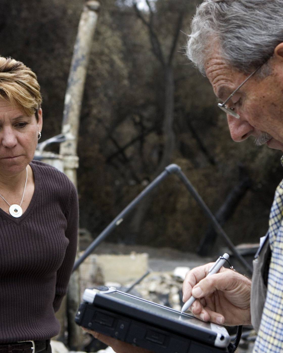 Inspector taking a renter's details after a wildfire destroyed her home