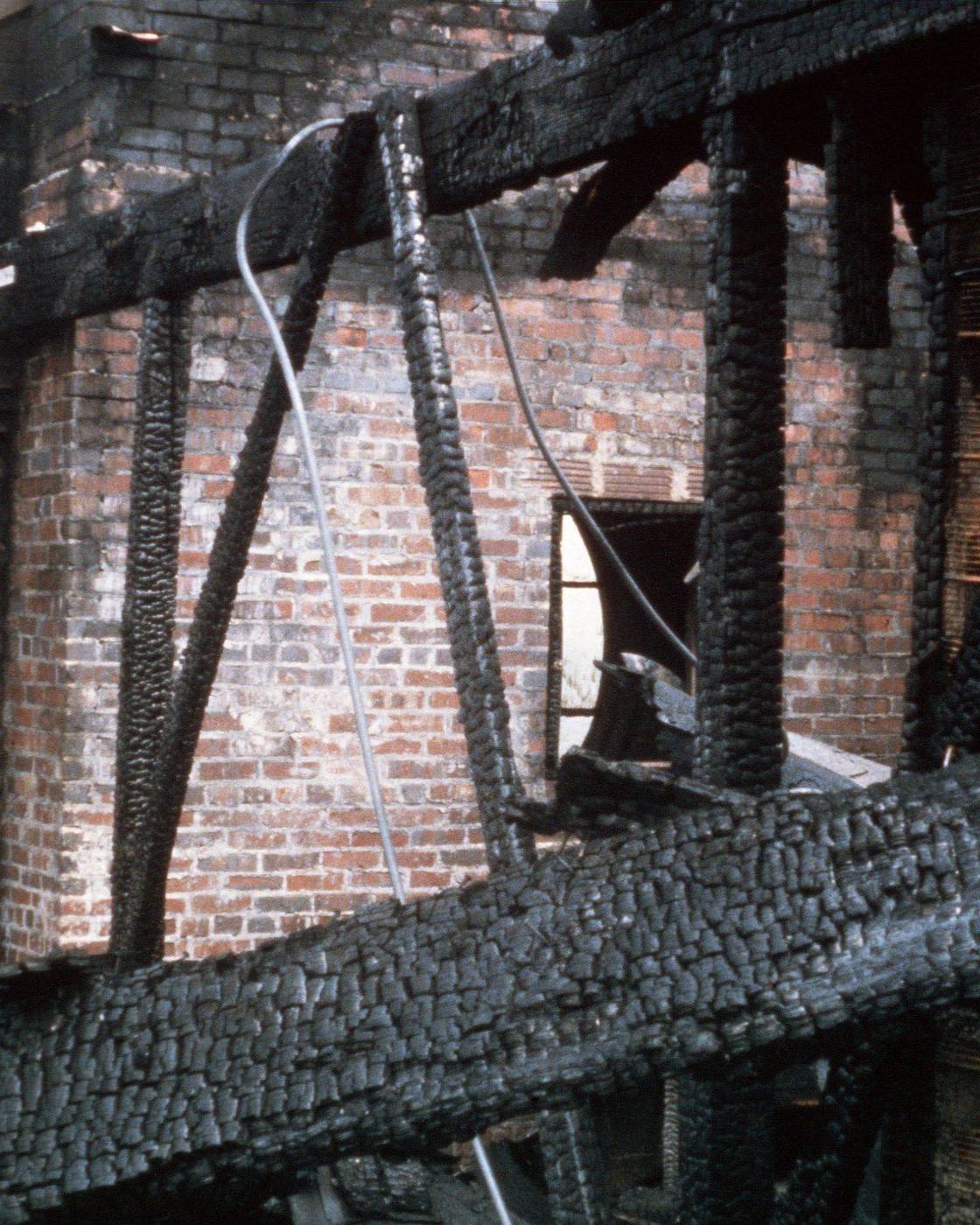 Fire investigator inspecting charred roof beams after a fire