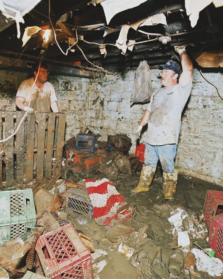 Two men mucking out a flooded basement