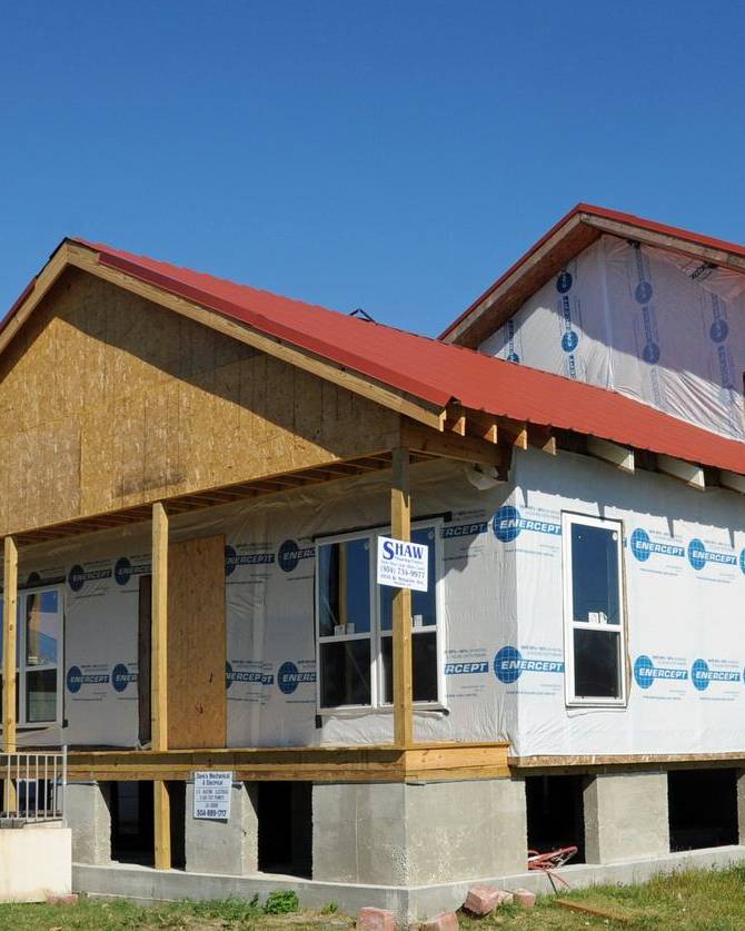Raised house under construction with house wrap and new framing