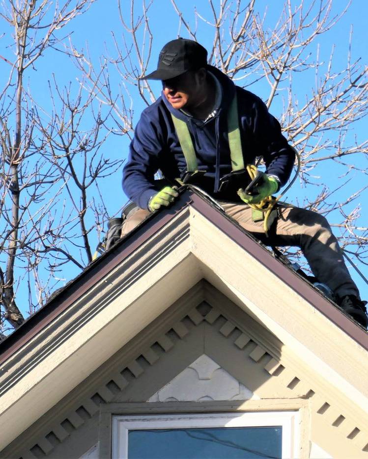 Two roofers working on the ridge of a house roof