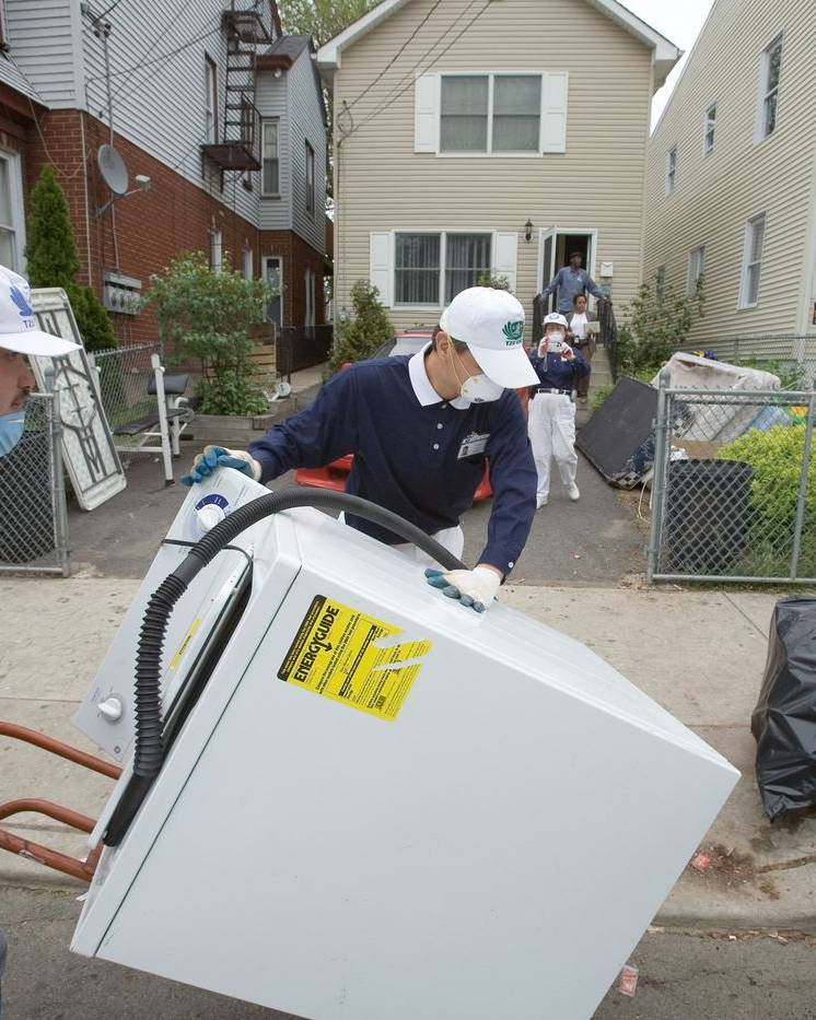 Volunteers carrying a ruined washing machine out of a flooded basement