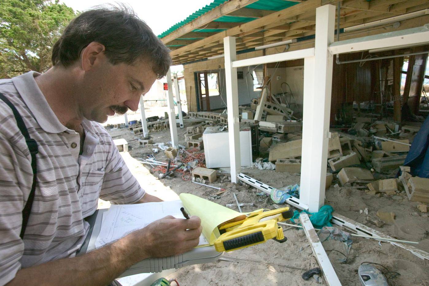 Insurance adjuster writing notes inside a storm-damaged house