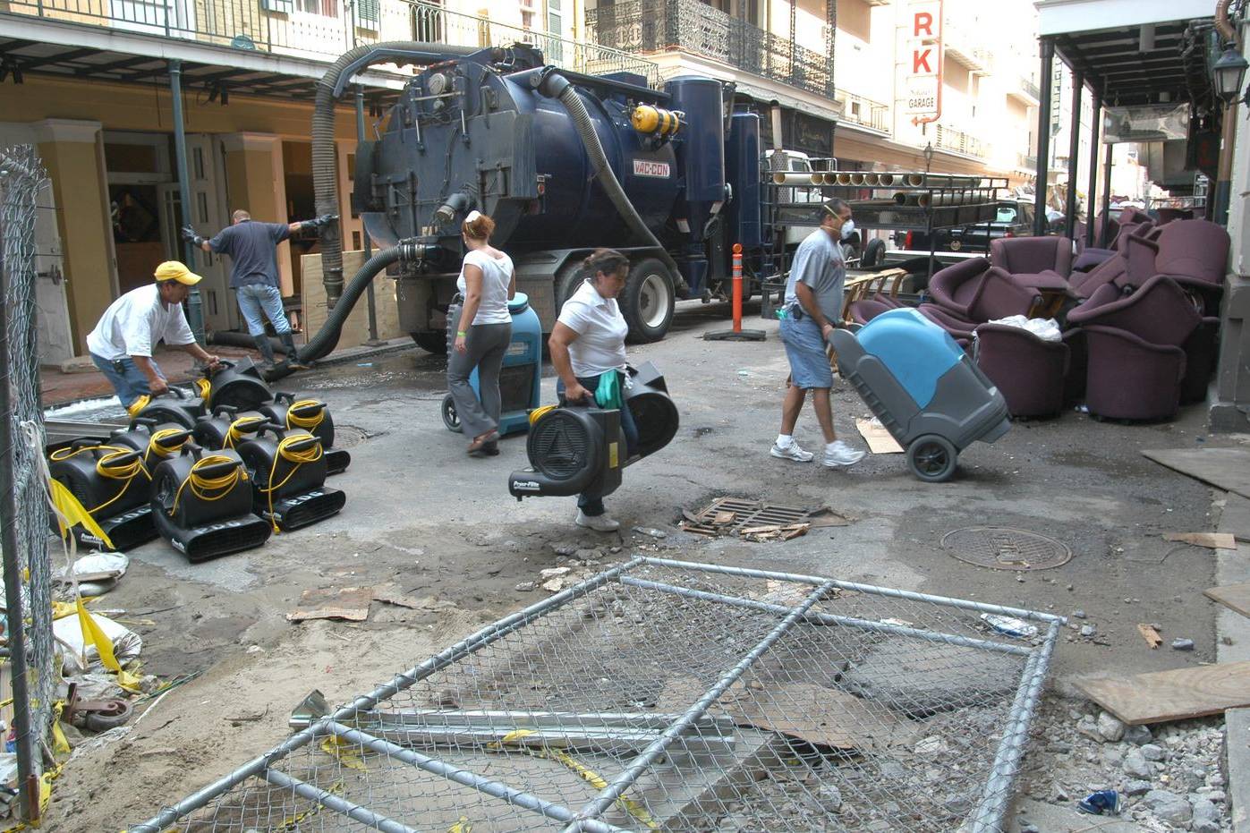 Cleaning crew carrying wet vacuums and drying fans into a flooded building