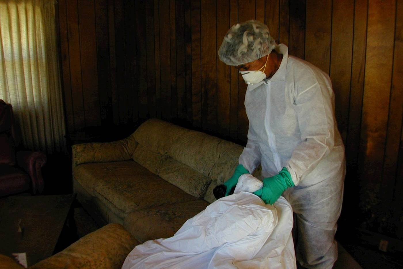 Homeowner in protective clothing cleaning mud and mold from her home