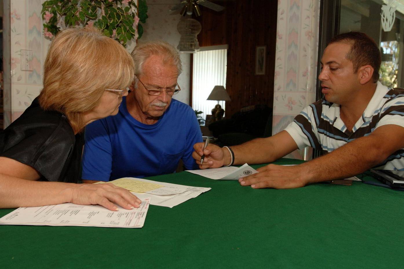 Couple going through forms with an inspector at their dining table