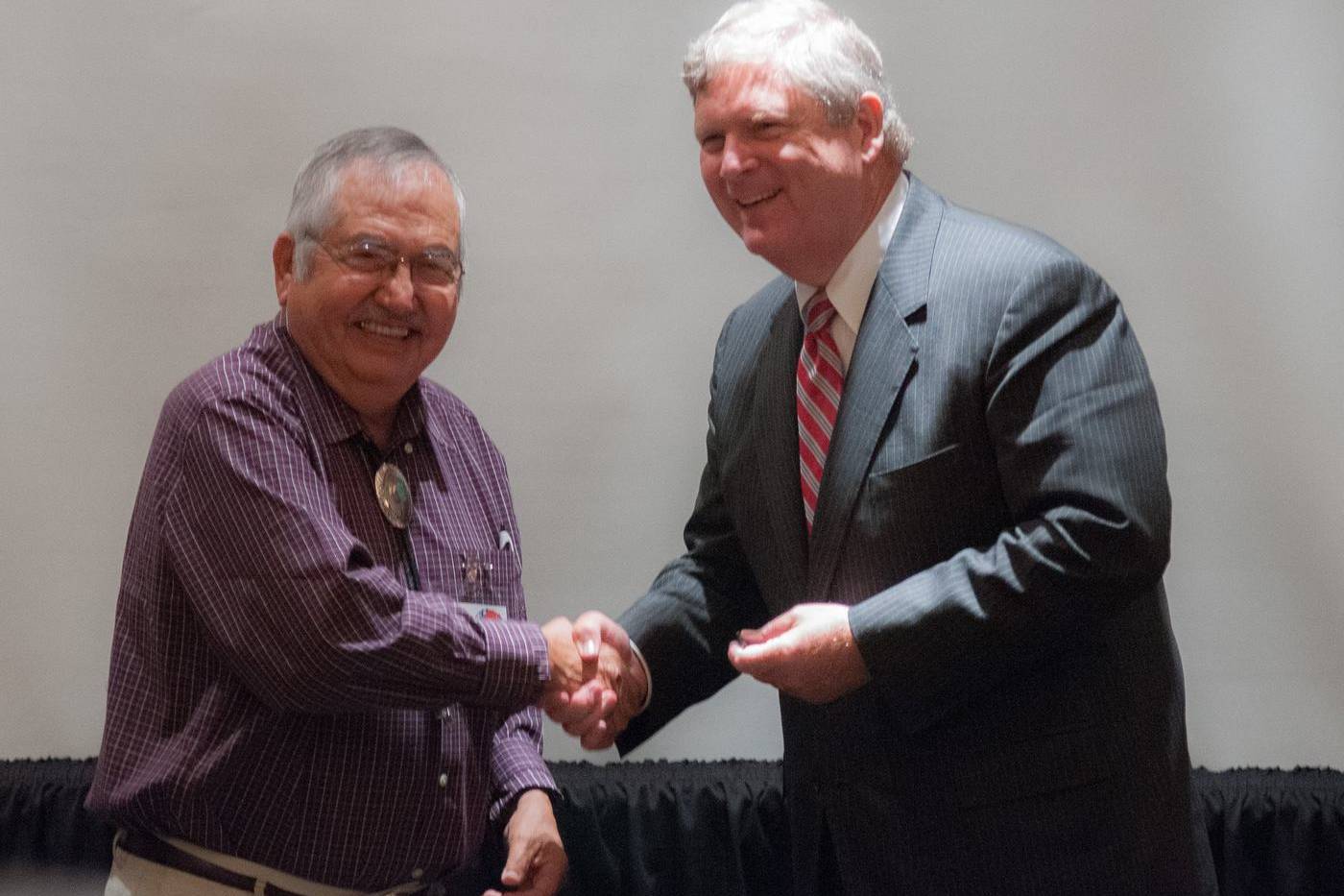Two men shaking hands at a meeting
