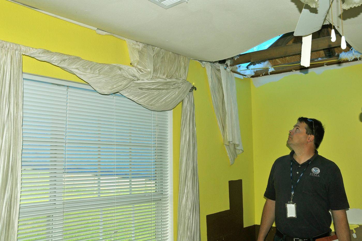 Inspector looking at a gap where a tornado lifted the roof off the wall
