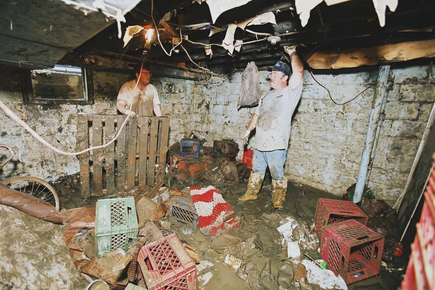 Two men mucking out a flooded basement