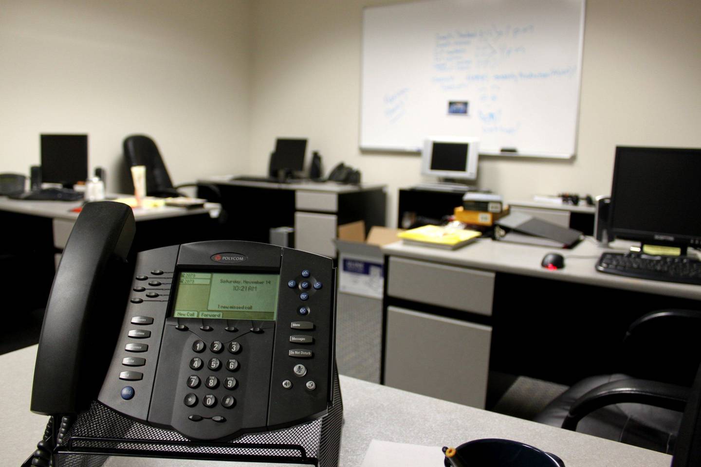 Office desks with a conference phone in the foreground