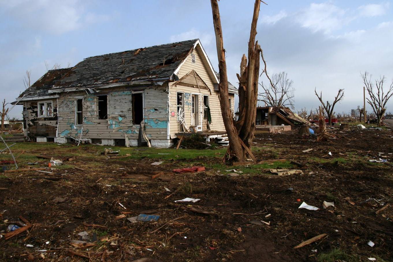House stripped by a tornado, with broken trees around it