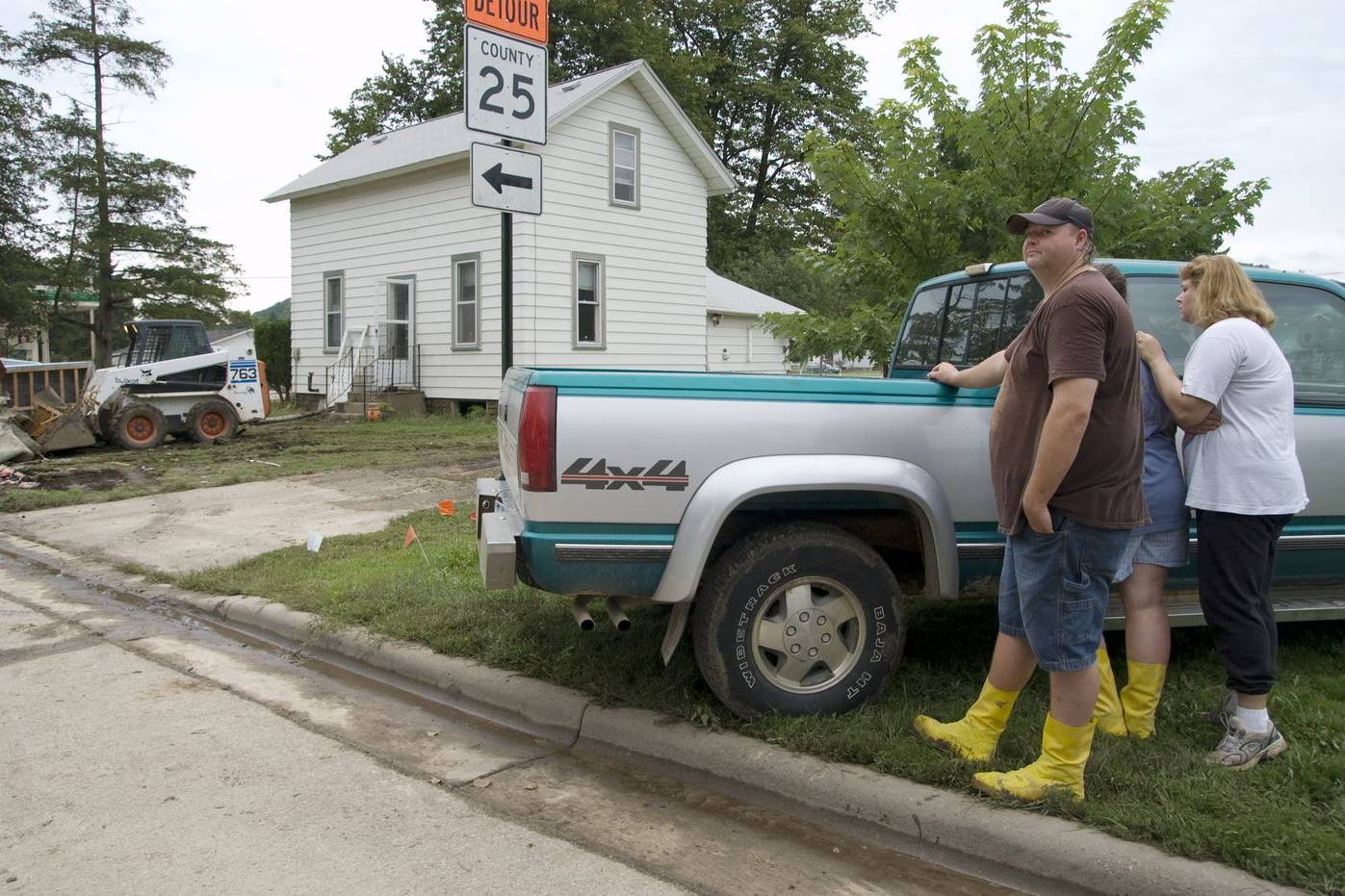 Residents watching volunteers clear debris from their flooded house