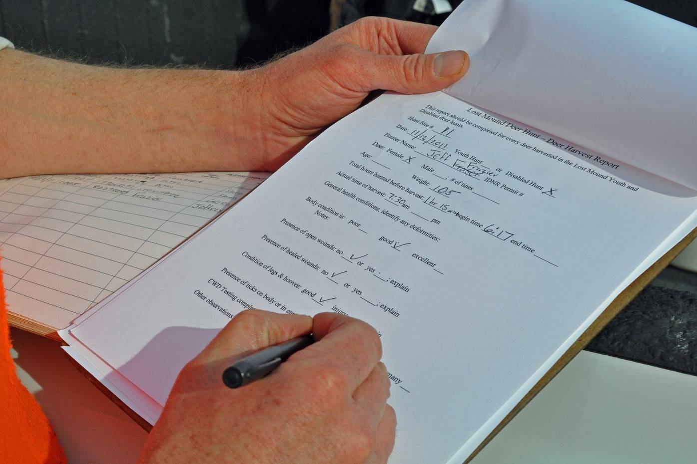 Close-up of a hand filling in a form on a clipboard